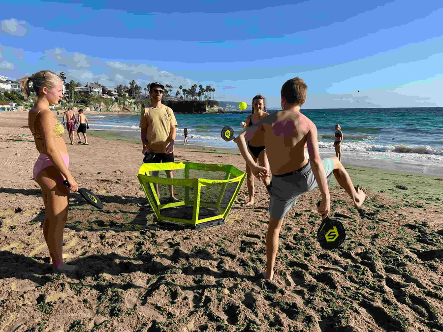 : A family playing at the beach, its a sunny day, the guy is performing a trick